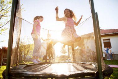  three adorable playful kids  jumping on trampoline outdoor  clipart