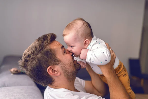 接近可爱的6个月大的高加索男婴咬爸爸的鼻子 英俊的年轻爸爸抱着孩子 牙齿成长的概念 — 图库照片