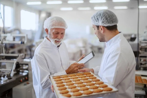 Jovem Funcionário Caucasiano Segurando Bandeja Com Biscoitos Frescos Enquanto Supervisor — Fotografia de Stock