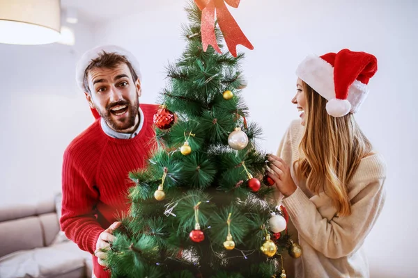 Vonzó Kaukázusi Pár Mikulás Sapkával Fején Díszített Karácsonyfával Pózol Miközben — Stock Fotó