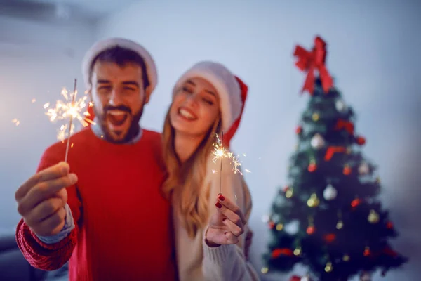 Feliz Casal Caucasiano Com Chapéus Papai Noel Cabeça Segurando Aspersores — Fotografia de Stock