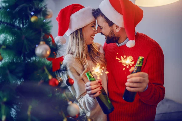 스웨터를 모자를 스프링클러와 맥주를 커플이다 앞쪽에 크리스마스 트리입니다 선택적으로 초점을 — 스톡 사진