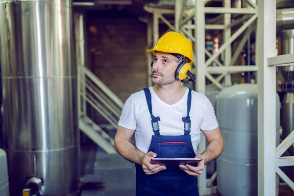 Serious Caucasian Worker Overalls Hardhat Head Antiphons Using Tablet While — Stock Photo, Image