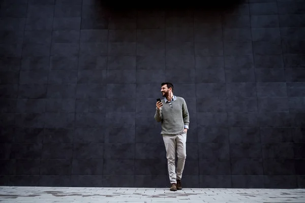 Handsome Fashionable Man Smiling Leaning Gray Wall Holding Smart Phone — Stok fotoğraf