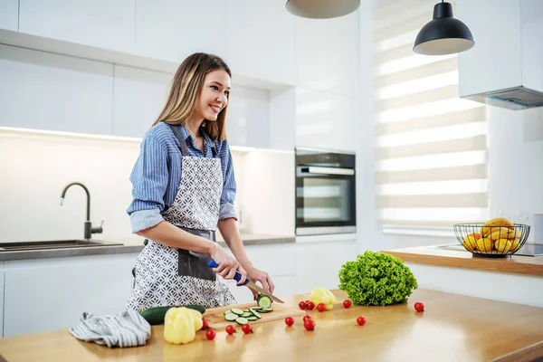 Jovem Mulher Caucasiana Feliz Avental Cozinha Corte Pepino Balcão Cozinha — Fotografia de Stock