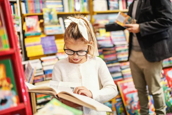 Adorable Curious Caucasian Little Girl Eyeglasses Standing Bookstore Reading Interesting — 스톡 사진