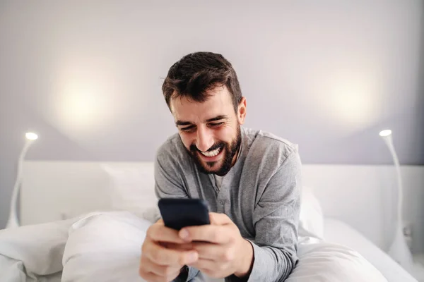 Joven Atractivo Sonriente Barbudo Caucásico Hombre Sentado Cama Dormitorio Uso —  Fotos de Stock