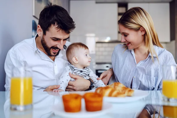 愛らしい男の子とダイニングルームに座っている若い幸せな両親 赤ん坊を抱えてるテーブルの上は朝食 — ストック写真