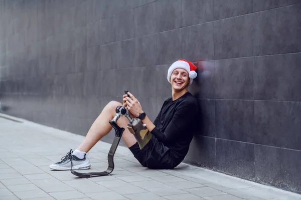 Cheerful Caucasian Sportsman Artificial Leg Santa Hat Head Sitting Ground — Stok fotoğraf
