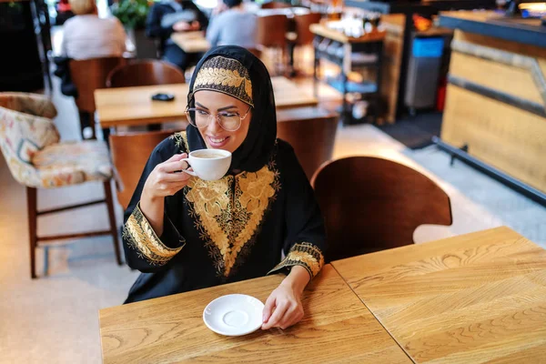 Hermosa Mujer Árabe Positiva Sonriente Ropa Tradicional Sentado Cafetería Solo —  Fotos de Stock