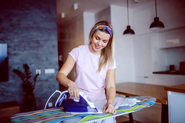 Hardworking Caucasian Smiling Blond Young Housewife Standing Living Room Ironing — Stok fotoğraf