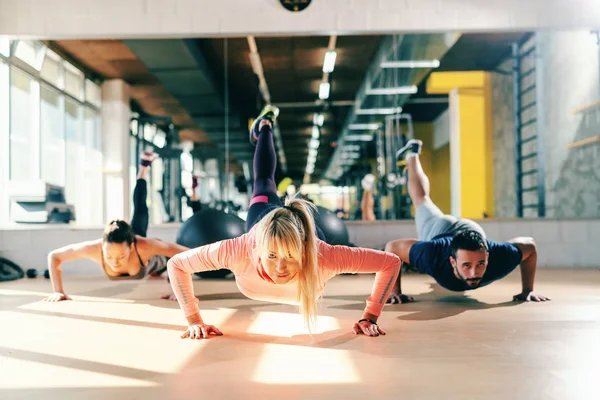 体育館の床で強度演習を行って健康的な習慣を持つスポーティな人々 のグループ 背景のミラーで — ストック写真