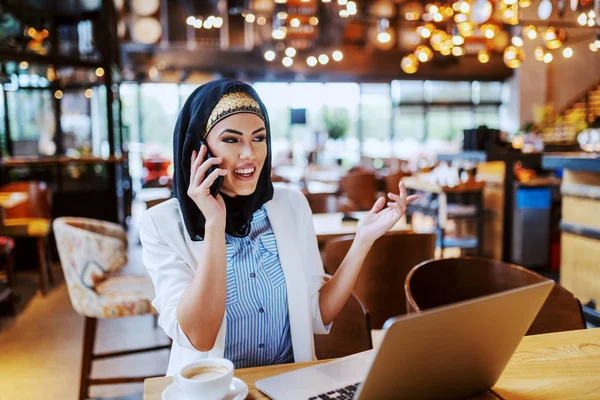カフェに座って上司と電話で話す素敵な若いイスラム教徒のファッショナブルなビジネス女性 テーブルにはコーヒーとノートパソコンがあります 千年世代 — ストック写真