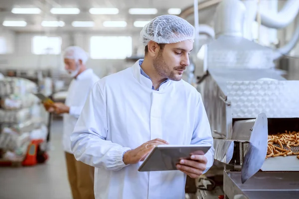 심각한 감독자는 태블릿을 들고있는 공장에서 식품의 품질을 유니폼 — 스톡 사진