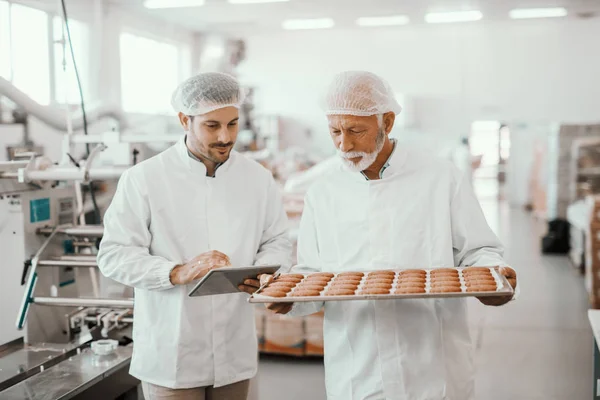 Vassoio Anziani Adulti Con Biscotti Freschi Mentre Supervisore Valuta Qualità — Foto Stock