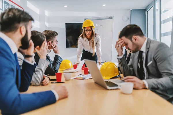 Atractiva Arquitecta Caucásica Apoyada Mesa Mirando Papeleo Colegas Escuchándola Hay — Foto de Stock