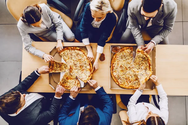 空腹の同僚のトップビューは テーブルに座って 昼食のためのピザを持っています 会社内部 — ストック写真