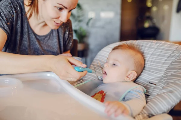 Önlüklü Beyaz Bir Erkek Bebek Koltuğunda Oturup Bebek Maması Yiyor — Stok fotoğraf