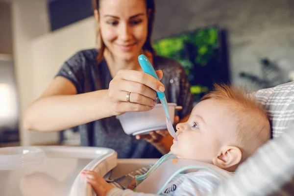 Önlüklü Beyaz Bir Erkek Bebek Koltuğunda Oturup Bebek Maması Yiyor — Stok fotoğraf