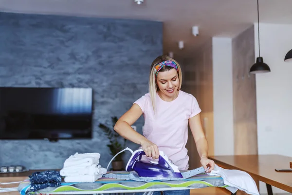 Lächelnd Fröhliche Kaukasische Blonde Junge Hausfrau Steht Wohnzimmer Und Bügelt — Stockfoto