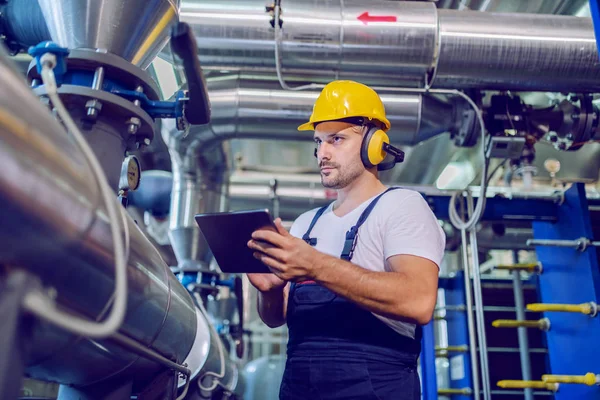 Travailleur Beau Sérieux Salopette Avec Casque Antiphons Utilisant Une Tablette — Photo