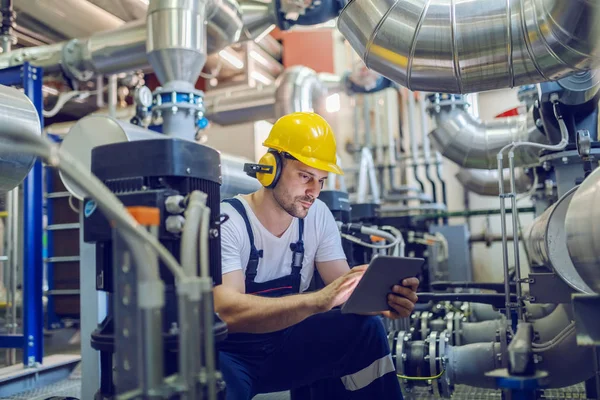 Serious Caucasian Handsome Worker Overall Hardhat Antiphons Crouching Using Tablet — 스톡 사진