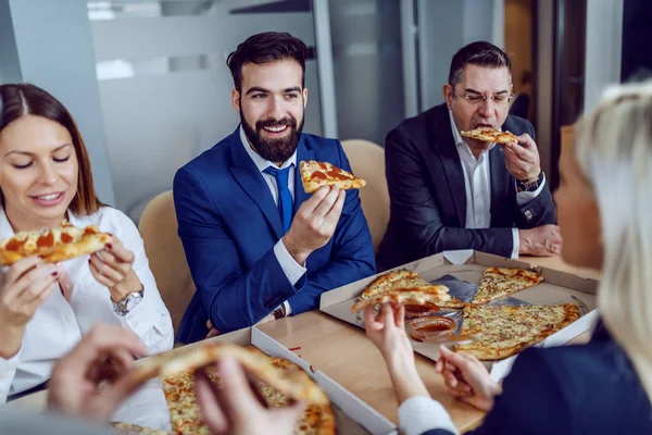 役員室に座っている間に昼食のためのピザを持っている空腹のビジネスの人々のグループ — ストック写真