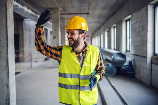 Smiling Positive Construction Worker Work Wear Standing Building Waving His — Stok fotoğraf