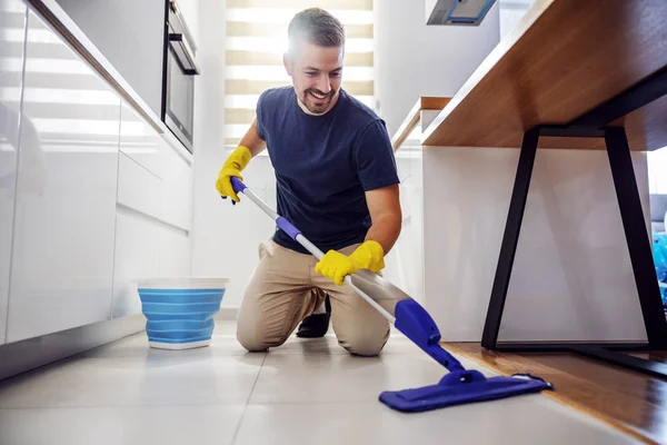 Ung Leende Positiv Skäggig Man Knäböjer Köksgolvet Använder Mopp Och — Stockfoto