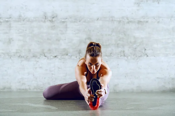 Dedicated Caucasian Sportswoman Sportswear Sitting Floor Stretching Leg — ストック写真