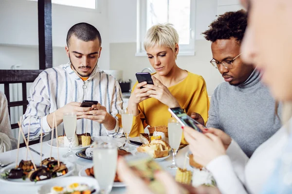 Grupo Amigos Multiculturales Sentados Mesa Comedor Para Almorzar Usar Teléfonos —  Fotos de Stock