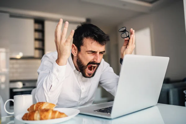 Giovane Uomo Barbuto Arrabbiato Seduto Tavolo Pranzo Casa Gridando Mentre — Foto Stock