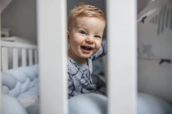 Roztomilý Smějící Blonďatý Chlapeček Krásnýma Modrýma Očima Sedící Ráno Postýlce — Stock fotografie