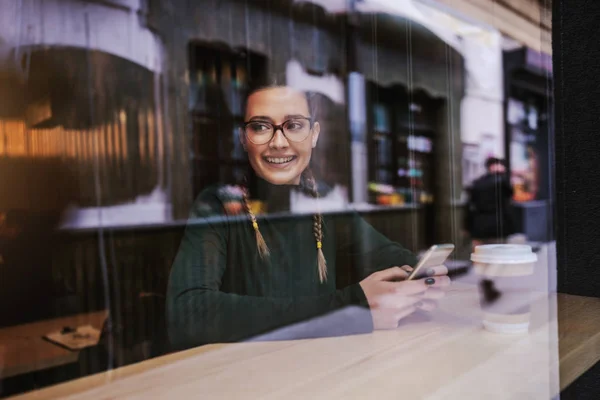 Mujer Joven Sonriente Sentada Cafetería Sosteniendo Teléfono Inteligente Ella Está — Foto de Stock