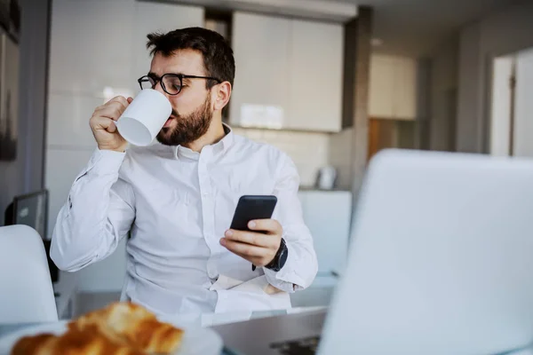 Joven Hombre Barbudo Guapo Alegre Sentado Mesa Comedor Casa Beber —  Fotos de Stock