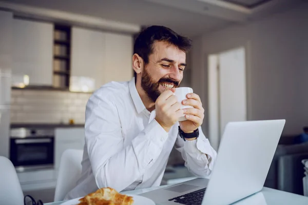 Fiatal Vidám Mosolygós Vonzó Szakállas Férfi Asztalnál Mailt Olvas Laptopján — Stock Fotó