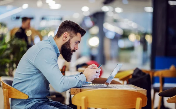 Vista Laterale Del Giovane Barbuto Seduto Nel Caffè Utilizzando Smartphone — Foto Stock