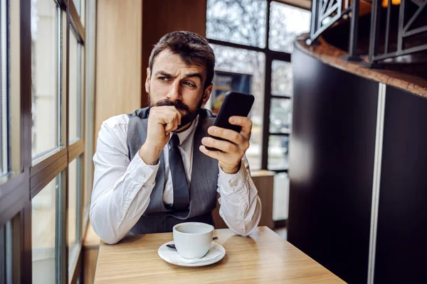 Jonge Verdachte Zakenman Zit Koffieshop Houdt Een Smartphone Vast Denkt — Stockfoto