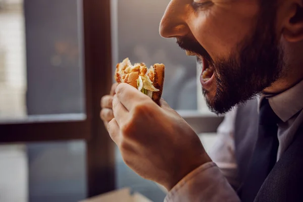 Éhes Öltönyös Férfi Aki Gyorskajáldában Sajtburgert Eszik — Stock Fotó