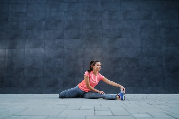 地面に広い足とストレッチ足に座って良い形で魅力的な健康的なスポーツ女性 ウォーミングアップ演習 — ストック写真