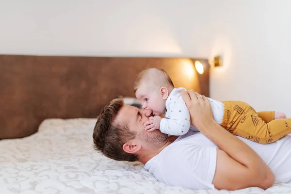 Sonriente Padre Guapo Caucásico Acostado Cama Dormitorio Sosteniendo Adorable Hijo —  Fotos de Stock