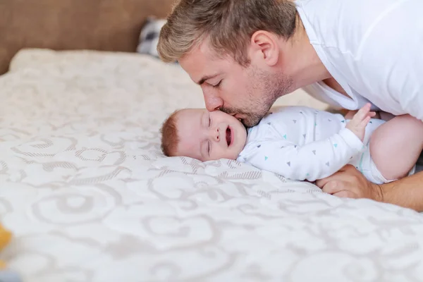 스러운 개월된 스러운 아들에게 애정어린 코카서스 젊은이의 아빠가 키스하는 침대에 — 스톡 사진