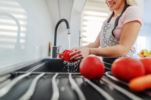台所の流しで赤唐辛子を洗うエプロンの白人女性の閉じる ランチの準備コンセプト — ストック写真