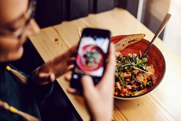 Kvinnan Fotograferar Sin Sallad När Hon Sitter Restaurangen Nära Fönstret — Stockfoto