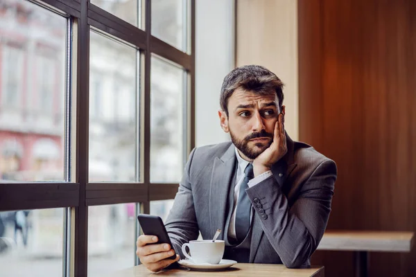 Jonge Bezorgde Zakenman Zit Koffieshop Houdt Een Smartphone Vast Denkt — Stockfoto