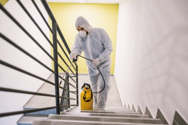 Sanitizing interior surfaces. Cleaning and Disinfection inside buildings, the coronavirus epidemic. Professional teams for disinfection efforts. Infection prevention and control of epidemic. Protective suit and mask. clipart