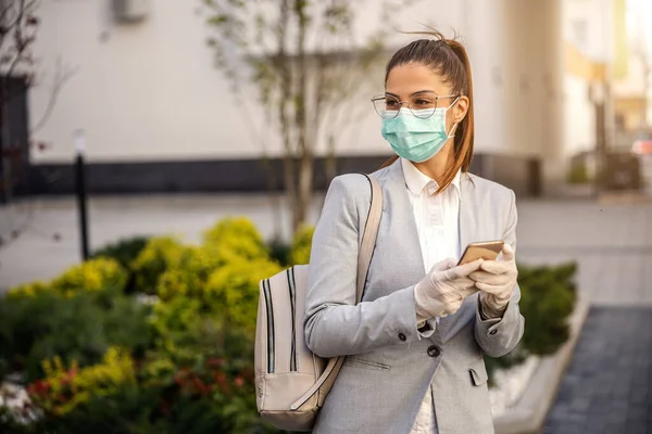 Young woman with mask and gloves typing on smartphone mobile phone, prevent infection of Covid-19 virus coronavirus,contamination of germs or bacteria. Infection prevention and control of epidemic. Protective suit and mask.