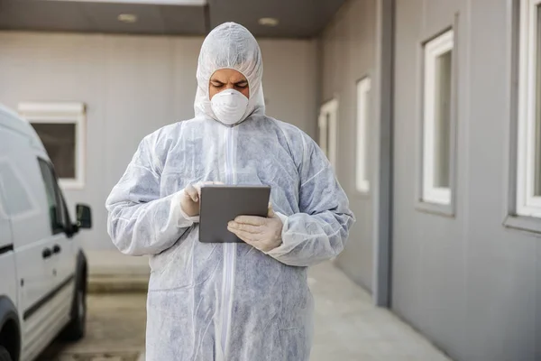 Hombre Traje Protector Virus Máscara Mirando Escribiendo Tableta Desinfectando Edificios —  Fotos de Stock