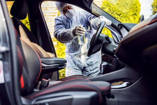 車内でマスク消毒と保護スーツの男 頻繁に触れられているきれいな表面を拭く Covid 19ウイルスコロナウイルスの感染を防ぐ 細菌や細菌の汚染 感染の予防と制御 — ストック写真