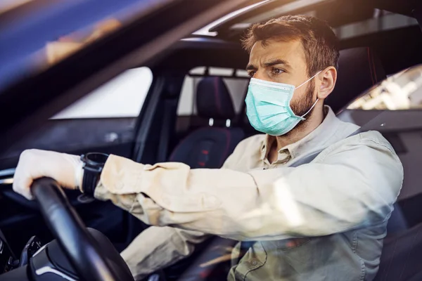 Man with protective mask and gloves driving a car. Infection prevention and control of epidemic. World pandemic. Stay safe.